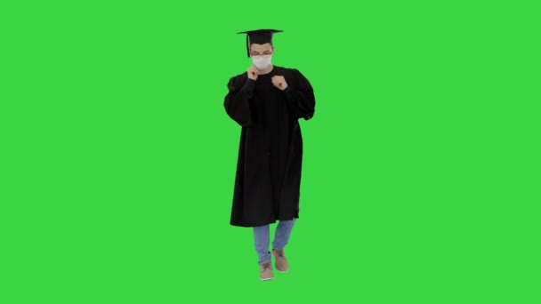 Végzős hallgató orvosi maszkban sétál a zöld vásznon, Chroma Key.