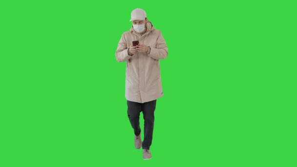 Junger, lässiger Mann, der in warmer Kleidung und Schutzmaske auf einem Green Screen einen Anruf tätigt, Chroma Key. — Stockvideo