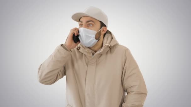 European young man calling with a medical mask on his face on gradient background. — Stock Video