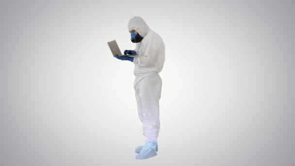 Arzt in weißer Schutzuniform mit Laptop auf Gradientenhintergrund. — Stockvideo