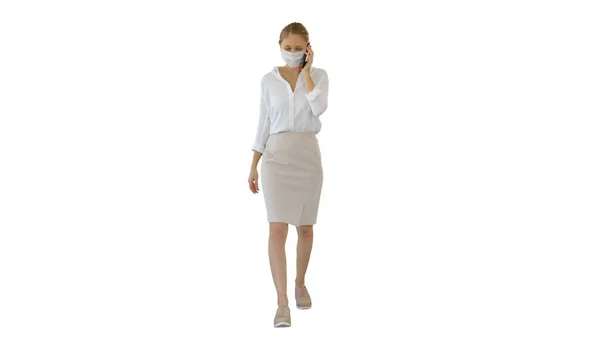 Jonge vrouw draagt Protective Face Mask maakt een oproep lopen op witte achtergrond. — Stockfoto