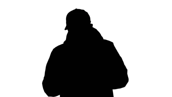 Silhouette Joven hombre casual caminando haciendo una llamada usando ropa de abrigo y máscara protectora . — Foto de Stock