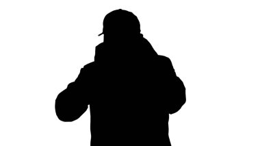 Siluet Avrupalı genç adam arıyor. Yüzünde tıbbi maske var..