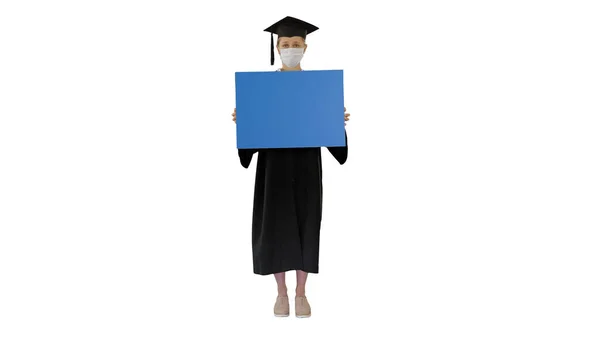 Graduate student meisje in bescherming masker houden blanco boord op witte achtergrond. — Stockfoto