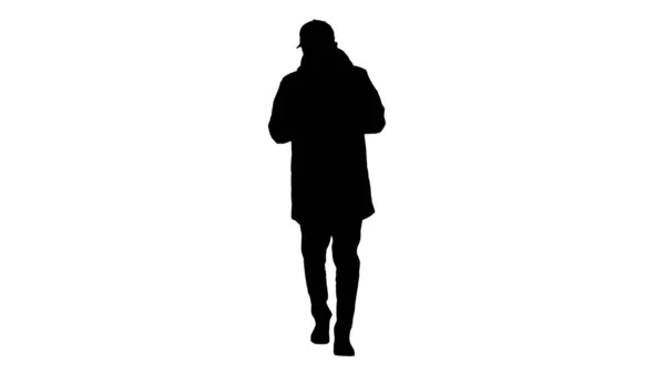 Silhouette Giovane uomo casual che cammina facendo una chiamata indossando vestiti caldi e maschera protettiva . — Foto Stock