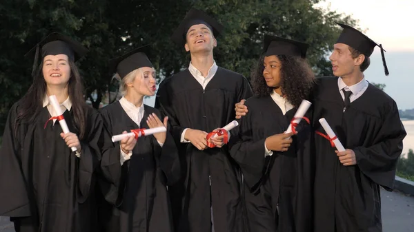 Groep afgestudeerde studenten die lopen en praten. — Stockfoto