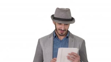 Beyaz arka planda tablet kullanan, şapkalı yakışıklı, gülümseyen bir Arap..