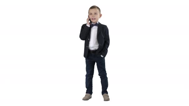 Schattig jongetje praten op zijn smartphone en staan in een donker pak op witte achtergrond. — Stockvideo