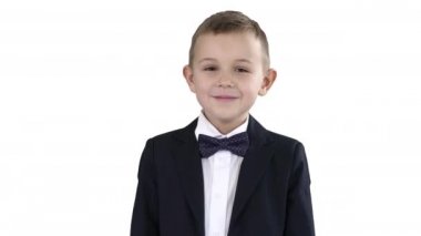 Beyaz arka planda duran resmi giyinmiş gülümseyen küçük çocuk..