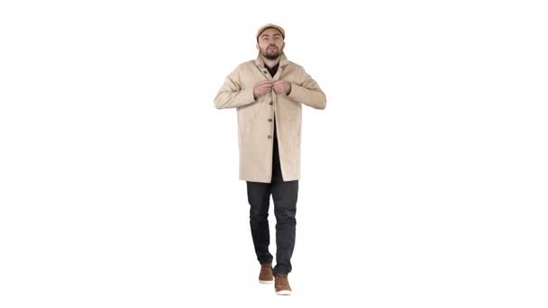 Jonge knappe man loopt en knoppen omhoog mantel op witte achtergrond. — Stockvideo