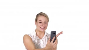 Pembe giyen kadın beyaz arka planda yürürken akıllı telefondan görüntülü arama yapıyor..