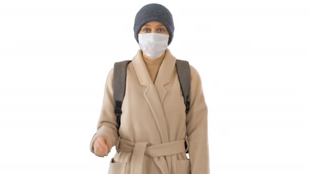 하얀 바탕에 코트를 입고 서 있는 의료용 마스크를 쓴 소녀. — 비디오