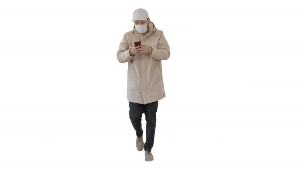 Young casual man walking making a call wearing warm clothes and protective mask on white background. — Stock Video