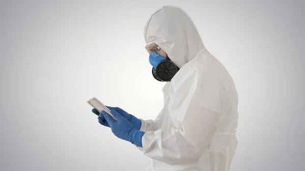 Médecin en costume de protection avec tablette numérique, concept Covid-19 sur fond dégradé . — Photo