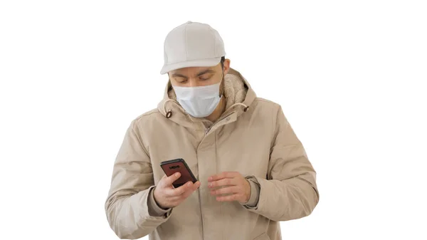 白い背景に暖かい服と保護マスクを身に着けている呼び出しを作って歩く若いカジュアルな男. — ストック写真