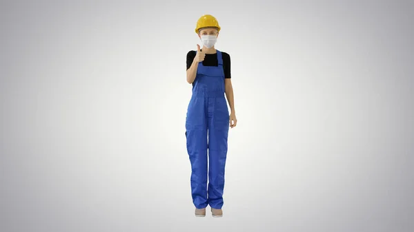 Kvinnlig byggarbetare sätta på medicinsk mask på lutning bakgrund. — Stockfoto
