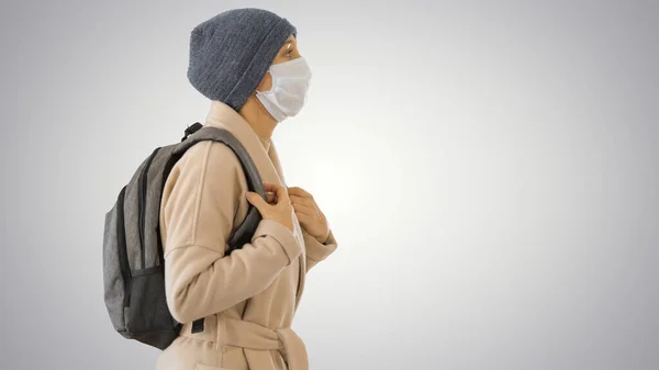 Covid-19 virus preventie, vrouw met een medisch masker op haar gezicht lopen op gradiënt achtergrond. — Stockfoto