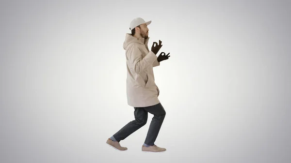 Hip-hop hombre cantando rap, caminando y haciendo gestos en el fondo gradiente . — Foto de Stock