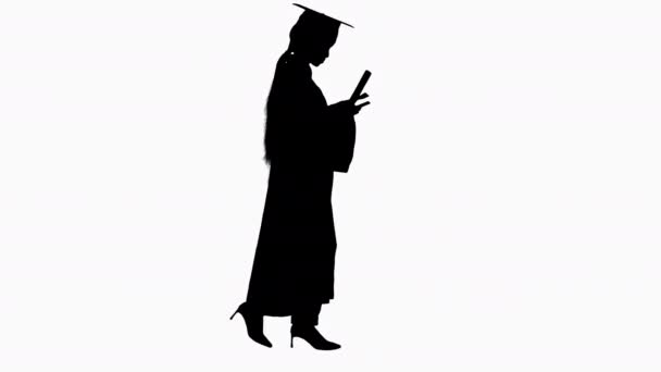 Silhueta jovem afro-americano menina estudante vestida com vestido de graduação preto segurando diploma e usando telefone celular . — Vídeo de Stock