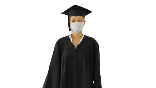 Kobieta Absolwentka w czapce i sukni noszącej maskę medyczną Chodzenie na białym tle. — Zdjęcie stockowe