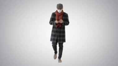 Tıbbi maskeli bir beyefendi telefon kullanıyor ve arka planda yürüyor..