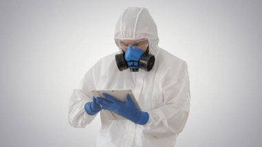Koruyucu kıyafetli erkek doktor, eğimli arkaplanda dijital tablet kullanıyor.