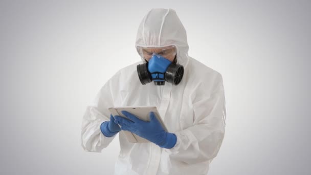 Médico masculino em traje de proteção usando comprimido digital em fundo gradiente . — Vídeo de Stock