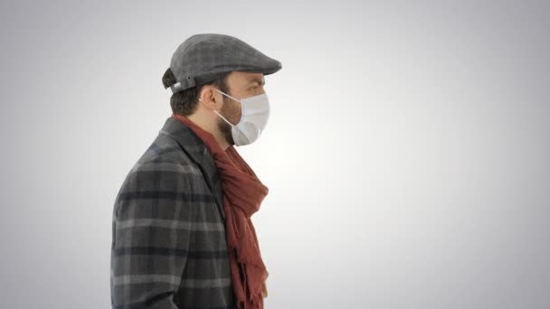 Cavalheiro vestindo uma máscara protetora andando sobre fundo gradiente . — Vídeo de Stock
