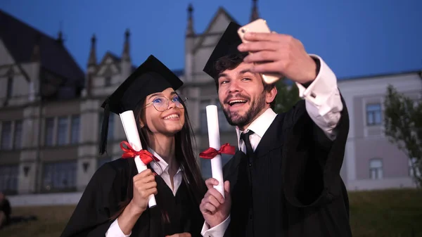 Garduate ζευγάρι κάνει μια selfie δείχνει διπλώματα στην κάμερα. — Φωτογραφία Αρχείου