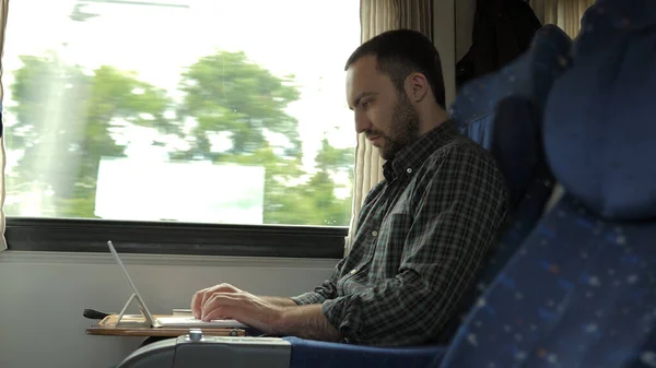 Hombre soñoliento trabajando en la tableta en el tren sentado junto a una ventana. — Foto de Stock