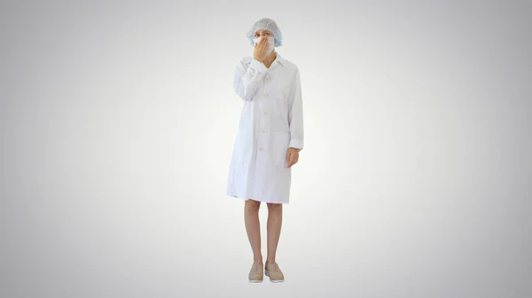 Tos Médico femenino en una máscara para evitar que otros de infección en el fondo del gradiente . — Foto de Stock