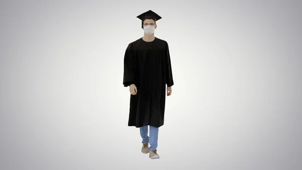 Выпускник в медицинской маске ходит на градиентном фоне . — стоковое фото