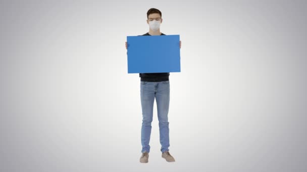 Studente in maschera medica con cartello bianco su sfondo sfumato . — Video Stock