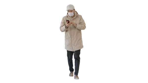 Jovem homem casual andando fazendo uma chamada vestindo roupas quentes e máscara protetora no fundo branco . — Fotografia de Stock