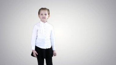 Sevimli küçük kız gülümsüyor ve özgüvenli bir şekilde arka planda kamerayla konuşuyor..
