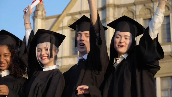 Щасливі молоді аспіранти демонструють свої дипломи . — стокове фото