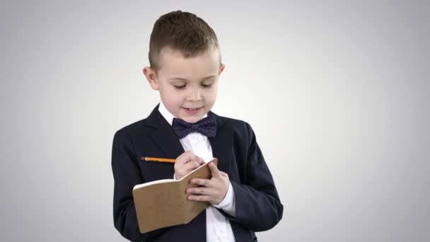 Junge in formeller Kleidung schreibt in Checkliste oder Notizbuch auf dem Hintergrund des Gefälles. — Stockvideo