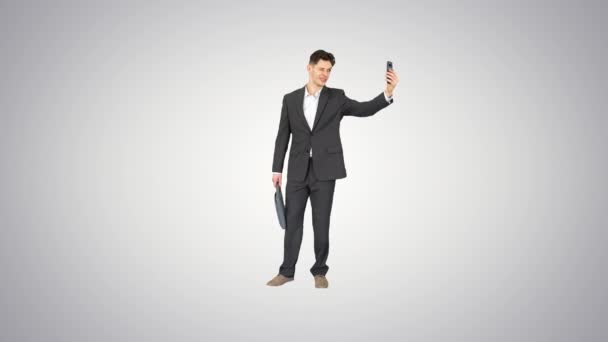 Ung affärsman tar selfie med sin telefon på lutning bakgrund. — Stockvideo