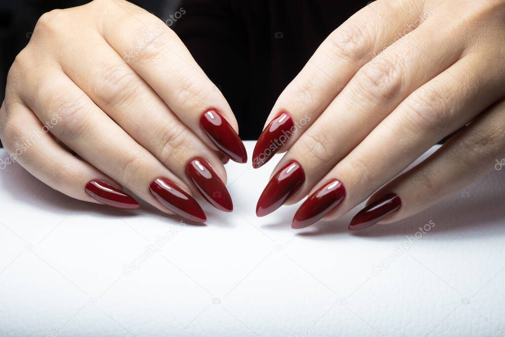 Woman showing manicured hands with red nail polish on white background.