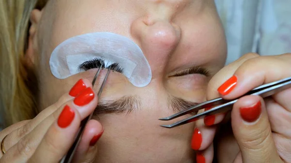 Procedimento de remoção de pestanas de perto. Mulher bonita com longas pestanas em um salão de beleza. Extensão das pestanas. — Fotografia de Stock