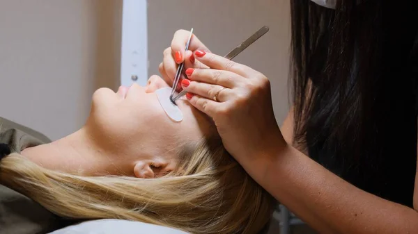 Eyelash extension procedure. The master grows long eyelashes. Female with extended eyelashes — Stock Photo, Image