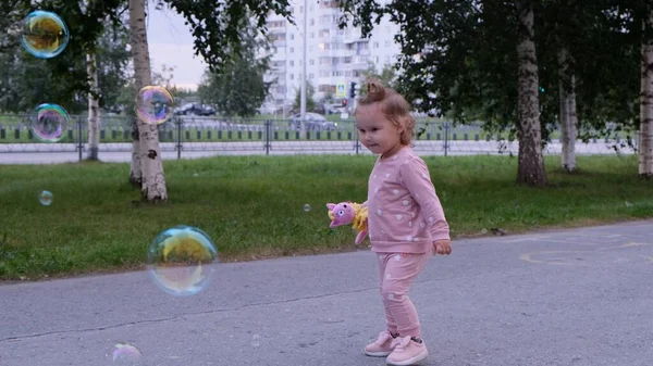 Gelukkig meisje loopt voor zeepbellen in het zomerpark. Gelukkig kindertijd concept. — Stockfoto