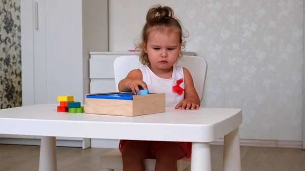 Menina, 2 anos, joga brinquedos educativos, pilhas e arranja figuras coloridas. Aprendizagem através de conceitos de experiência, habilidades motoras grosseiras e finas — Fotografia de Stock