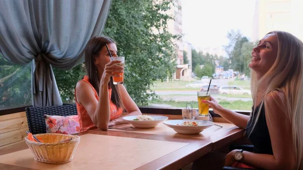 Dvě módní dívky, přátelé, Blondýnka a brunetka popíjí koktejly v kavárně. — Stock fotografie