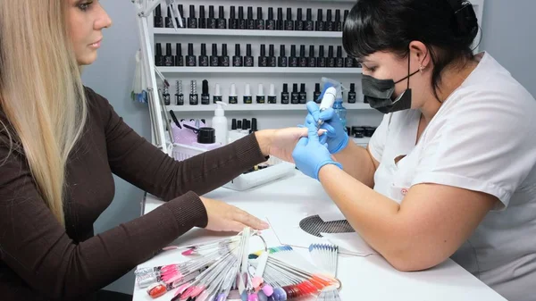 Nizhnevartovsk, Rusya - 12 Ağustos 2019: donanım manikürü. Manikürcü kadın için güzellik salonunda manikür yapıyor. Manikür ustası tırnak etlerini söker. Ağır çekim. Donanım manikürü