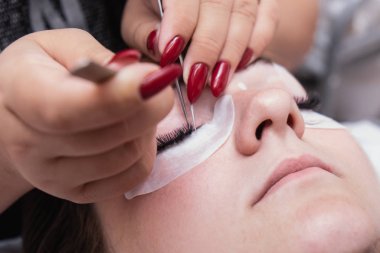 Kirpik uzatma ustası uzun kirpikleri güzellik salonunda güzel bir kız. Kirpik uzatma işlemi.