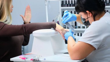 Closeup çekim tarafından bir güzellik tırnak törpüsü ile manikür alma bir tırnak salonu içinde bir kadın. Kadın Başlarken tırnak manikür. Şevval Özçelik Güzellik dosya bir müşteriye çivi.