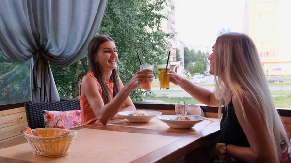 Dwie szczęśliwe piękne dziewczyny bawią się w kawiarni w słonecznym letnim dniu. — Zdjęcie stockowe