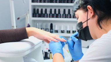 Manikürcü güzellik salonunda güzel bir elin tırnaklarını boyuyor. Jel cilası. Lacquer. Manikür. Çivi uzantısı