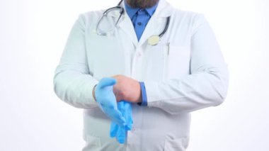  Doktor, beyaz üniformalı bir adam mavi eldivenlerini giyer ve beyaz arka planda elini çıkarır.